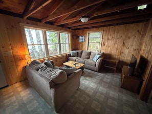 L’intérieur d’un chalet accueillant, avec un canapé, une petite table et un téléviseur.