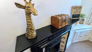 Ett svart konsolbord med en gyllene giraffskulptur, en liten bok med läderinbundet omslag och en skylt med texten: ”Välkommen att använda vårt Wi-Fi”.