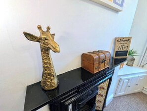 Ein schwarzer Konsolentisch mit einer goldenen Giraffenskulptur, einem kleinen ledergebundenen Buch und einem Schild mit der Aufschrift 'Welcome to use our WiFi'.