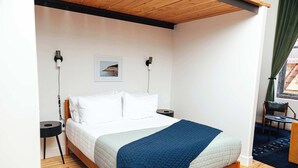 A bedroom with a bed, bedside tables, a wall-mounted picture, and a window with curtains. - Loft 309 @The William | Records, Brick & Character (Birmingham)