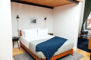 Ein Schlafzimmer mit Bett, Nachttischen, einem Wandbild und einem Fenster mit Vorhängen.