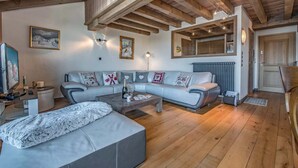 Een moderne woonkamer met een hoekbank, een salontafel, een televisie en een open haard.