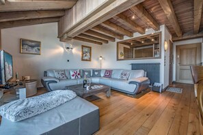 Ein modernes Wohnzimmer mit einer Eckcouch, einem Couchtisch, einem Fernseher und einem Kamin.