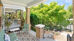 Un espace extérieur abrité, doté d’une terrasse, de sièges et offrant une vue sur les arbres.