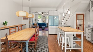 Une cuisine spacieuse avec un coin repas, des meubles blancs et un escalier menant à un autre niveau.