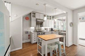 A modern kitchen with white cabinetry, a wooden island, and pendant lighting. - Hill East, Barney Circle 2-BR, Walk to METRO Stop (Washington)