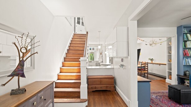 Un intérieur moderne avec un escalier en bois, des murs blancs et une bibliothèque bleue.