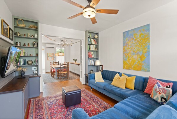 A living room with a blue sofa, a wooden ceiling fan, and a bookshelf. - Hill East, Barney Circle 2-BR, Walk to METRO Stop (Washington)