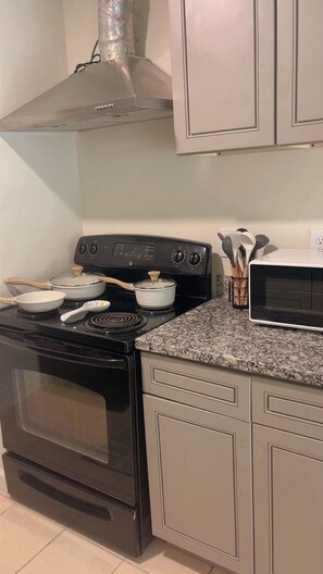 A kitchen with a stove, oven, microwave, and cabinets.