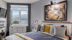 Un dormitorio con cama, ventana con vistas, un cuadro colgado y chimenea.