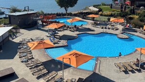 Un resort con una piscina grande, sillones de descanso y vistas a las montañas.