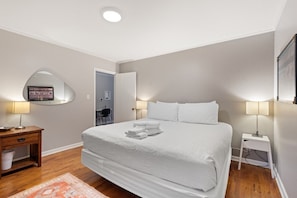 Une chambre à coucher comprenant un lit, des tables de chevet, un miroir, un bureau et une chaise.