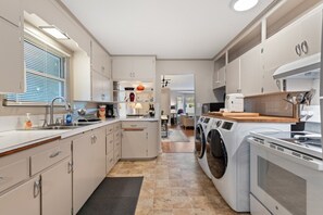 Une cuisine moderne dotée d’appareils électroménagers intégrés, d’un lave-linge et d’un coin repas visible à travers une porte ouverte.