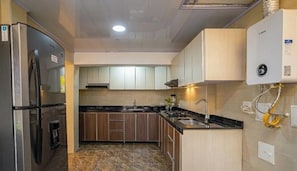 Eine Küche mit Kühlschrank, Herd, Spüle und Boiler.