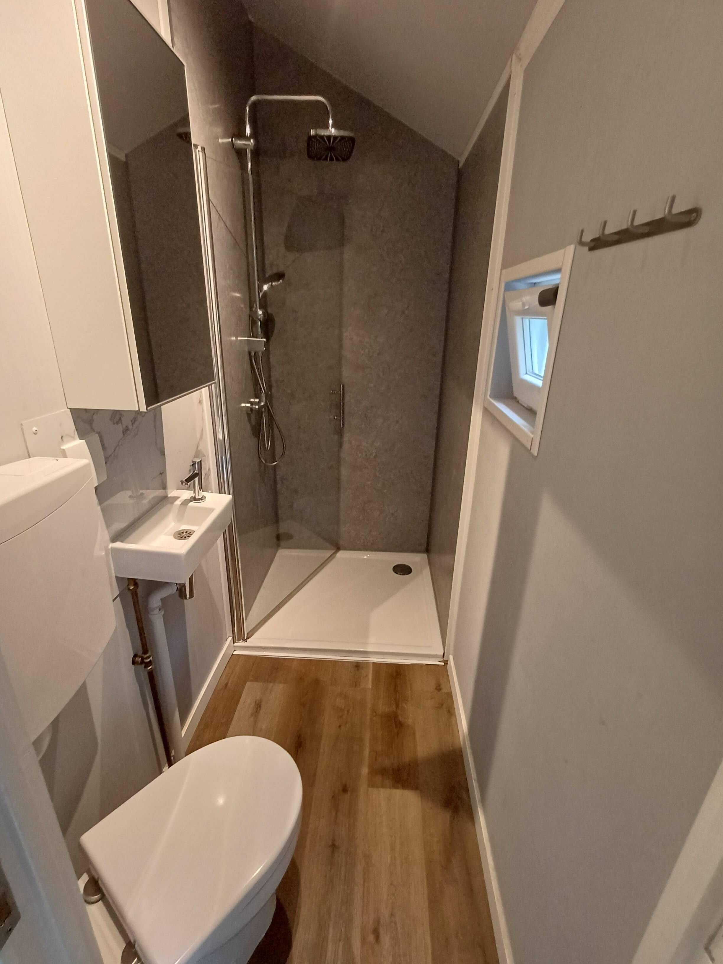 Een moderne badkamer met een douche, toilet en wastafel.