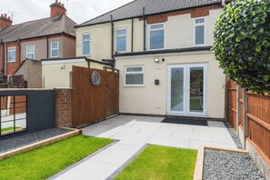 A residential property with a paved patio, a wooden fence, and a well-maintained lawn. - Heath Lodge - Stockingford, Nuneaton (Warwickshire)