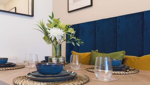 A dining table with blue bowls, clear glasses, and a vase with white flowers.
