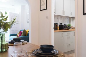 A modern kitchen with white cabinets, a coffee machine, and a countertop with various items. - Heath Lodge - Stockingford, Nuneaton (Warwickshire)