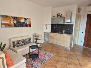 A modern apartment with a living room, kitchenette, and a zebra-themed painting. - Charming apartment in Porto Cervo, Sardegna. (Porto Cervo)