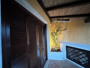 A covered outdoor area with a wooden door, a potted plant, and a stone floor. - Charming apartment in Porto Cervo, Sardegna. (Porto Cervo)