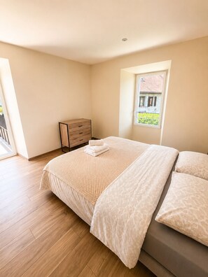 A bedroom with a bed, a dresser, a window with a view, and wooden flooring. - A - Le cottage des Belhiardes - 100m from the lake (Saint-Jorioz)