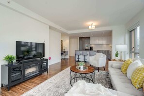 Ein modernes Wohnzimmer mit Flachbildfernseher, Sofa, Couchtisch und Essbereich mit Stühlen.