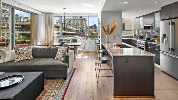 A modern apartment with a living area, kitchen, and large windows overlooking a cityscape.