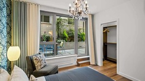 A bedroom with a large bed, a chandelier, a window with a view of the outdoors, and a built-in wardrobe.