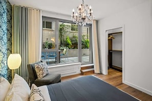 Ein Schlafzimmer mit einem großen Bett, einem Kronleuchter, einem Fenster mit Blick ins Freie und einer integrierten Garderobe.