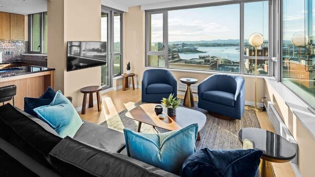 Ein modernes Wohnzimmer mit einer Couch, Sesseln, einem Couchtisch und einem Fernseher.