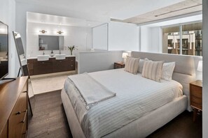 A modern bedroom with a large bed, a vanity with a mirror, and a view of the city through a large window. - Executive Luxury Loft in Downtown Victoria (Victoria)