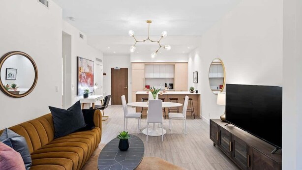 A modern living room with a sofa, coffee table, TV, and a kitchen in the background. - Affluent Executive Suite w/ Parking (Victoria)