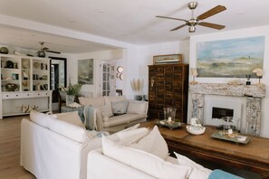 A spacious living room with a white sofa, a wooden cabinet, and a fireplace.