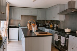 A kitchen with light blue cabinets, a black countertop, a stove, and a dishwasher.