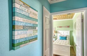 A room with a bed, a wall with inspirational phrases, and a door leading to another room. - Charming St. Augustine Retreat Near Butler Beach with AC (St. Augustine)