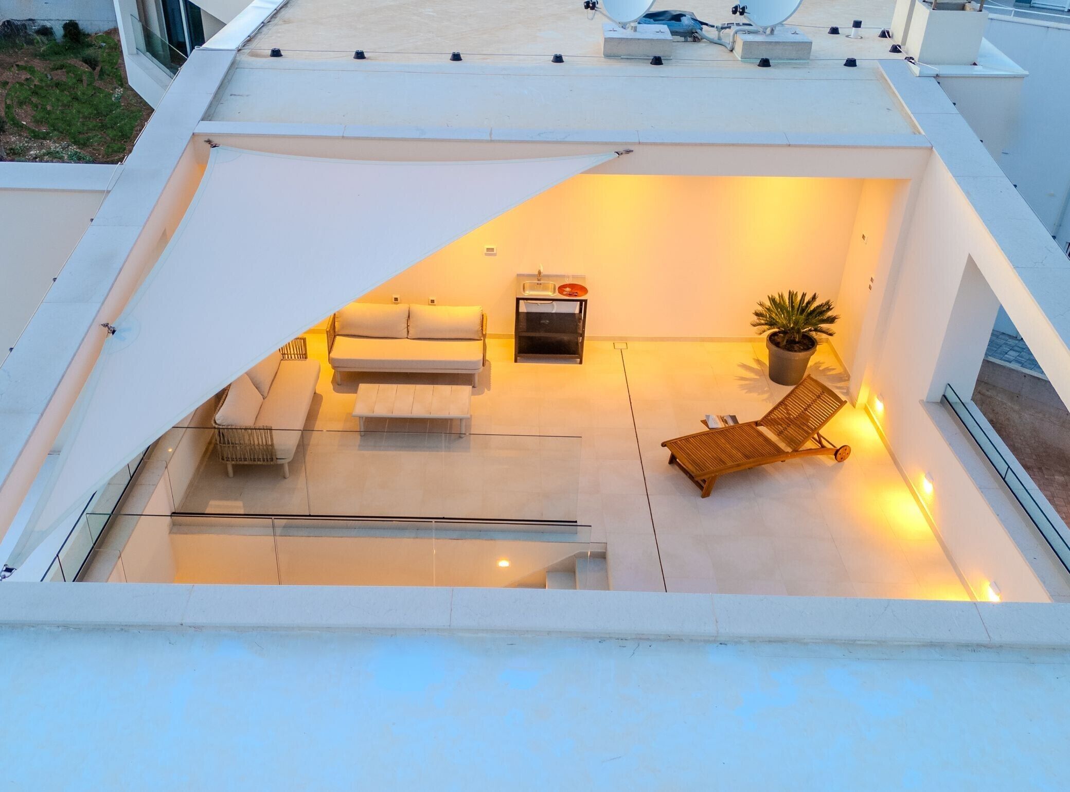 Eine Dachterrasse mit einer Couch, einem kleinen Tisch, einem Stuhl und einem Blumentopf.