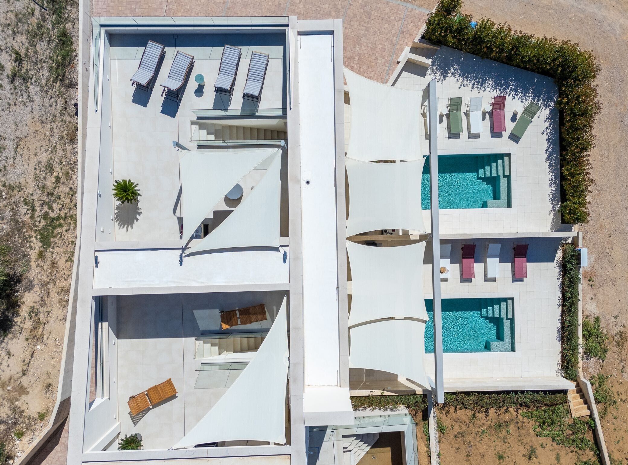 Un edificio moderno con piscina en la azotea, varios sillones de sol y una escalera que lleva a un nivel superior.
