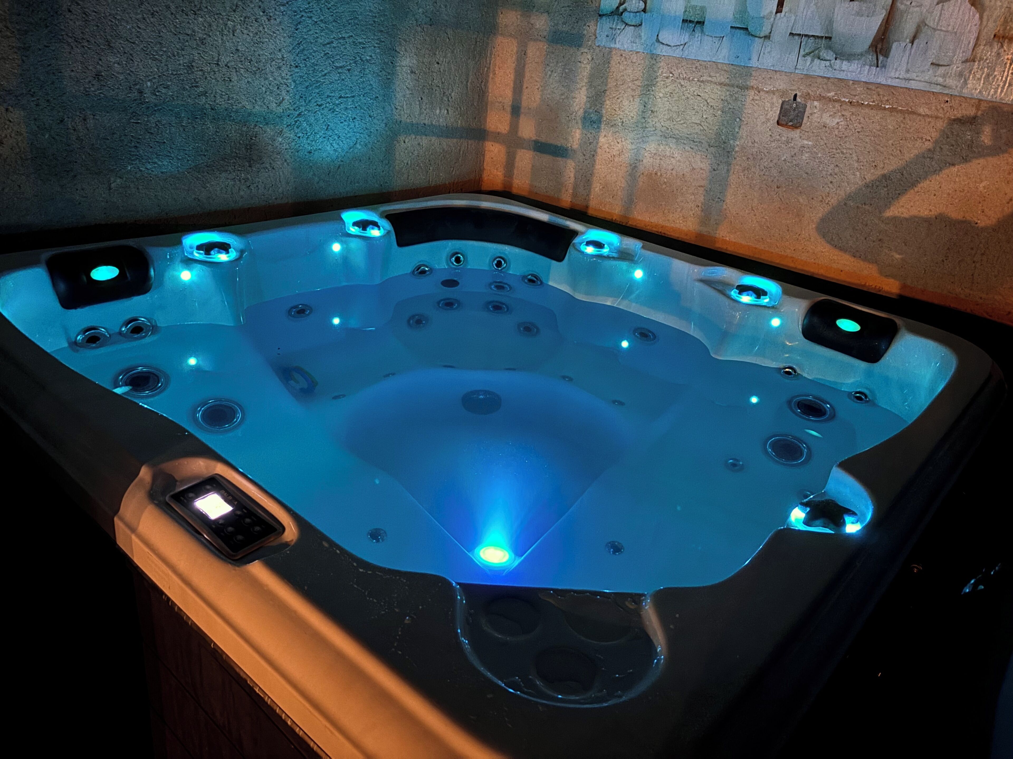 Un jacuzzi con múltiples chorros, un panel de control y una luz azul.