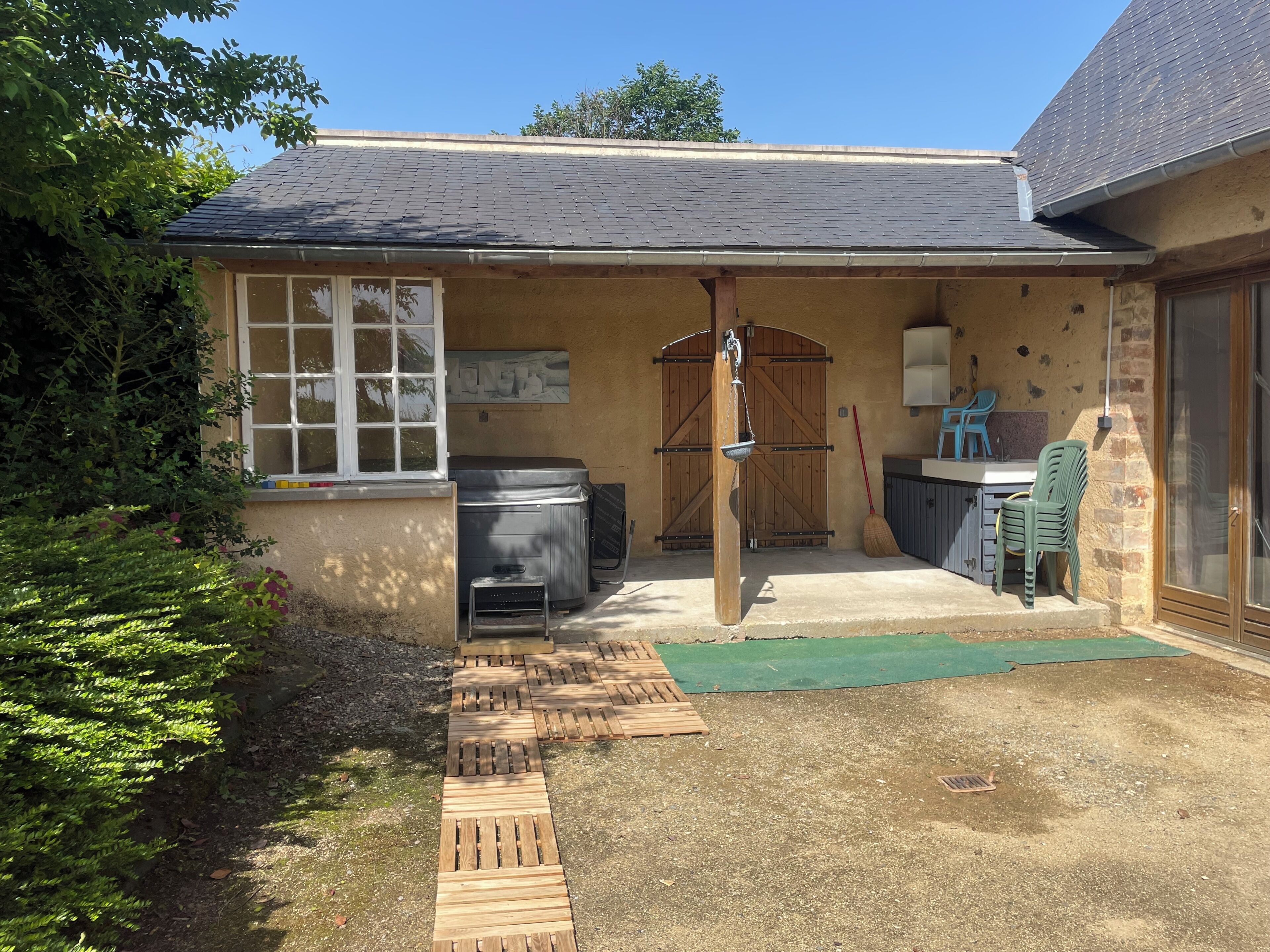 Une petite maison avec un patio, un jacuzzi, une porte en bois et une fenêtre.
