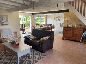 Ein Wohnzimmer mit einer Couch, einem Tisch, einem gemusterten Teppich, einem Holzschrank und einer Treppe.