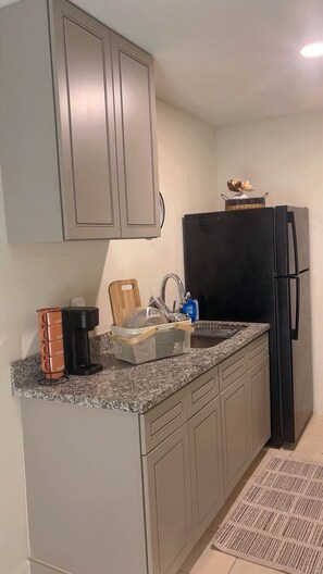 A kitchen with a granite countertop, a black refrigerator, and a sink with a faucet. - Houston Cozy 1-bedroom condo easy access to FWY unit 41 (Houston)