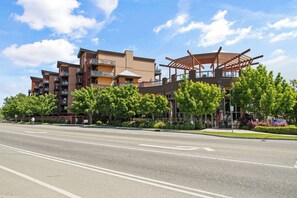 A multi-story building with balconies, a covered outdoor area, and a clear sky.