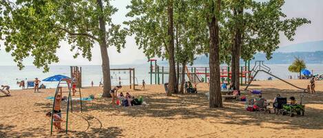 A beach with trees, a playground, and people.