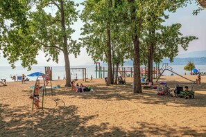 A beach with trees, a playground, and people.