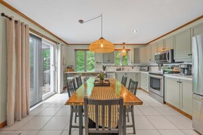 A modern kitchen with a dining area, large windows, and a sliding glass door.