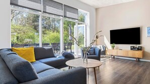 Una sala de estar moderna con un sofá grande, una mesa de centro y un televisor montado en la pared.