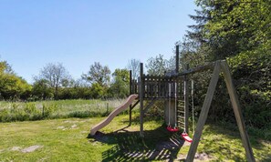 A playground with a slide and swings. - 5 Star Holiday Home in Glesborg (Glesborg)