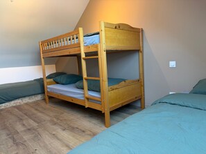 A bunk bed with a ladder, a single bed, and a wall-mounted light fixture.