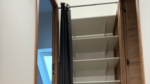 Ein Zimmer mit Holzboden, einer Decke mit Oberlicht und einem Schrank mit Regalen.