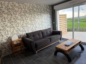 Un salon moderne avec un canapé gris, une table d’appoint en bois et une table basse originale dotée de grandes roues.